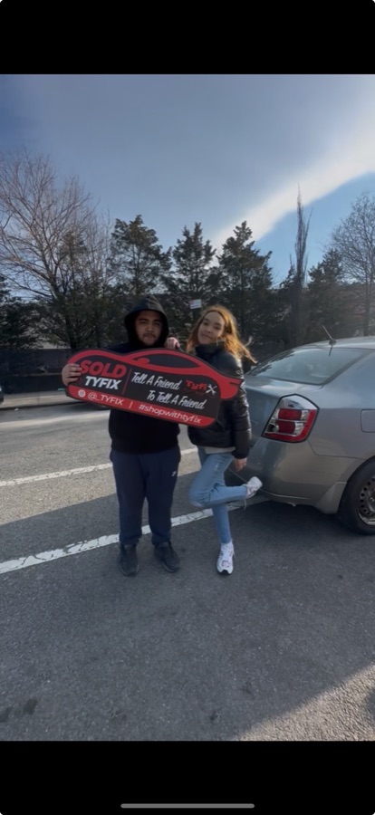Two customers collecting a sedan, holding the TyFix SOLD key